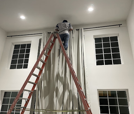 cropped view of handyman in uniform holding hammer while repairing roof